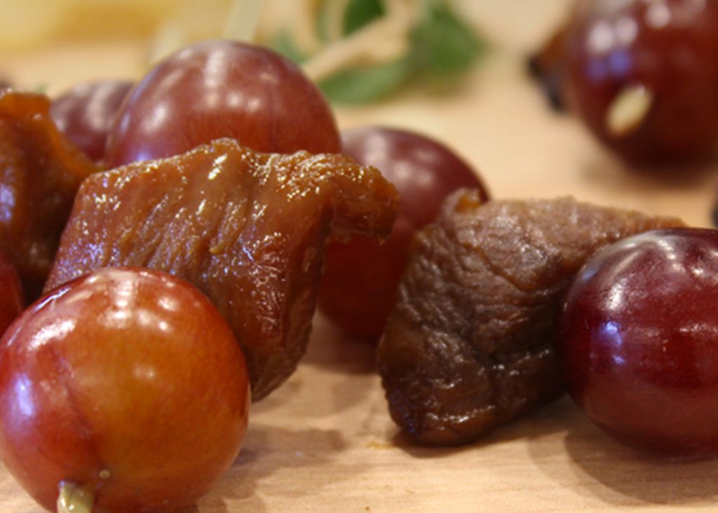 Hors-d’œuvre de brochettes de poitrine de canard en cubes laqué à l’orange et aux raisins